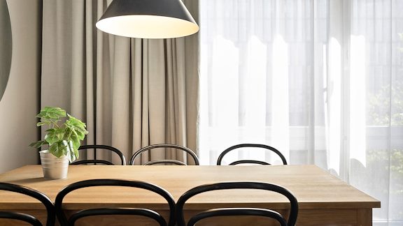 Ett köksbord med sex stolar. En lampa hänger från taket.