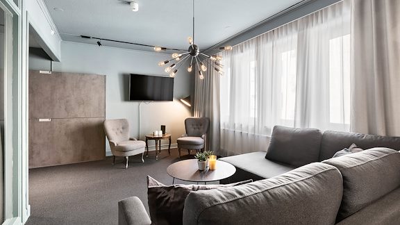 Ett vardagsrum i ett hotellrum. En soffa med ett runt bord och en tv på väggen.