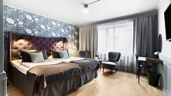 Ett hotellrum med en dubbelsäng. Parkettgolv.