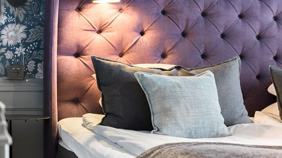 En hotellsäng med tre dekorativa kuddar.