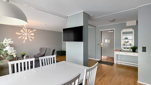 Ett stor hotellrum med köksbord, soffdel och tv.