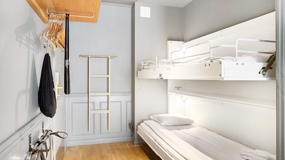 En dubbelsäng i ett hotellrum. En klädhängare hänger på väggen.