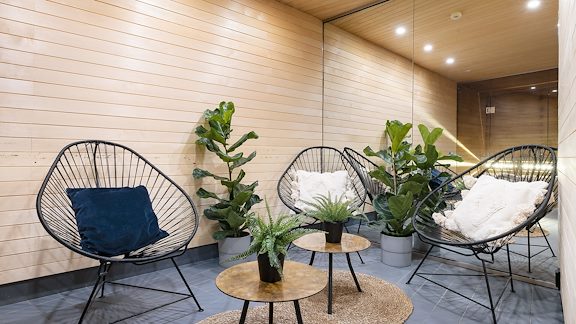 Relaxdel utanför bastun på Princess Hotel. Tre trådstolar runt två små bord. Blomdekor.